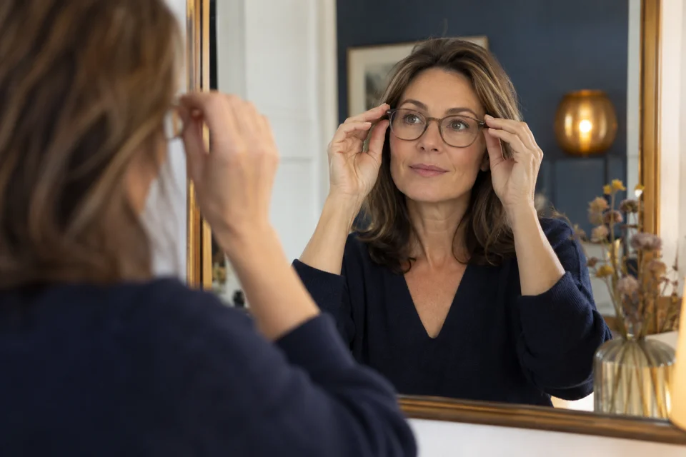Vrouw controleert de pasvorm van haar bril in een spiegel